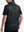 Back upper body shot of model wearing black grey leaf2  full print quarter zip sleeveless vest pullover