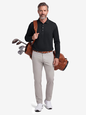 Front full body shot of model wearing black solid stretch cotton pique long sleeve polo shirt while carrying a golf bag on back