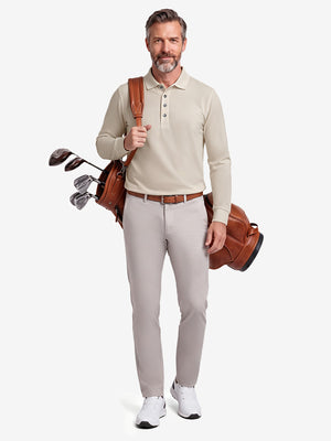 Front full body shot of model wearing light khaki solid stretch cotton pique long sleeve polo shirt while carrying a golf bag on back