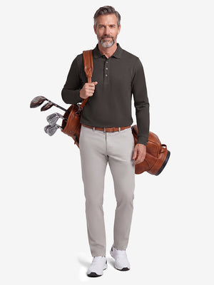 Front full body shot of model wearing dark brown solid stretch cotton pique long sleeve polo shirt while carrying a golf bag on back