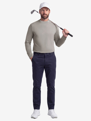 Front full body shot of model wearing sand warm brushed mock neck golf t shirt with golf club resting on shoulder