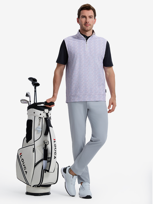 Front full body shot of model wearing colorful hexagon full print quarter zip sleeveless vest pullover with one hand resting on golf bag