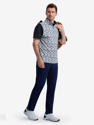 Front full body angled shot of model wearing black grey leaf1 full print quarter zip sleeveless vest pullover while carrying a golf bag in one hand