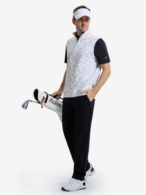 Front full body angled shot of model wearing brown grey camo  full print quarter zip sleeveless vest pullover while carrying a golf bag in one hand
